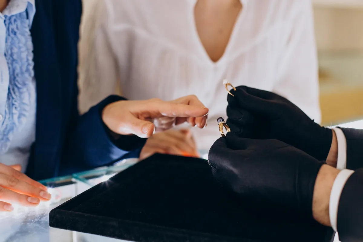 Jeweler in black gloves examining a ring across a counter during an appraisal