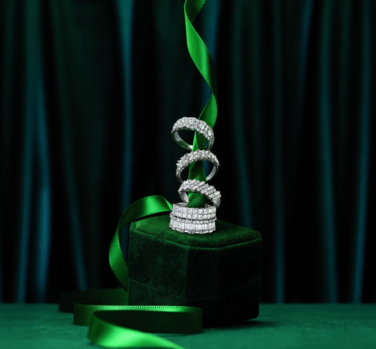 Diamond ring displayed on a dark green velvet stand with a green ribbon