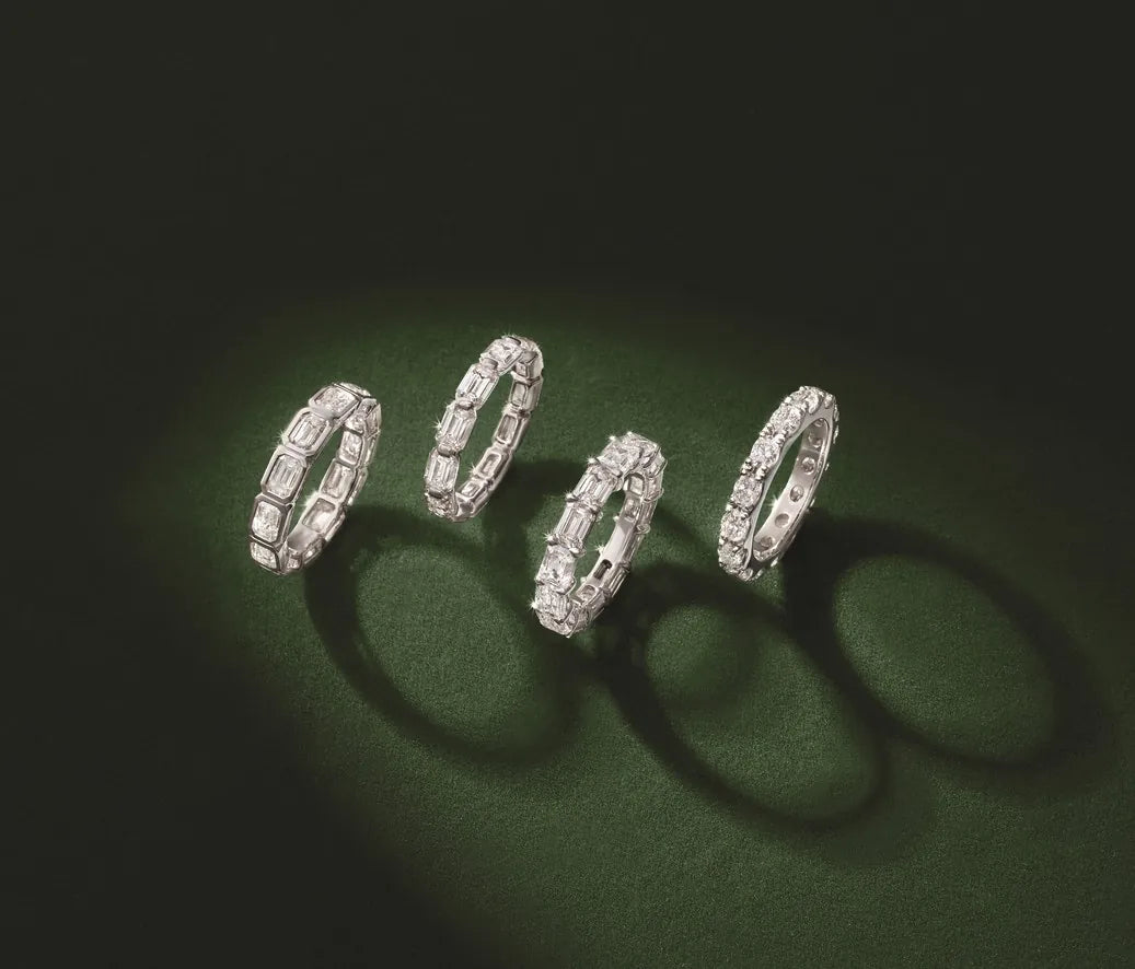 Four diamond rings with shadows on a dark green surface