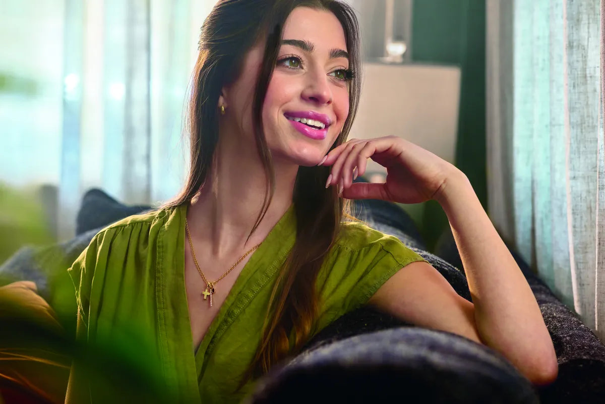 Smiling woman in a green top wearing a gold necklace