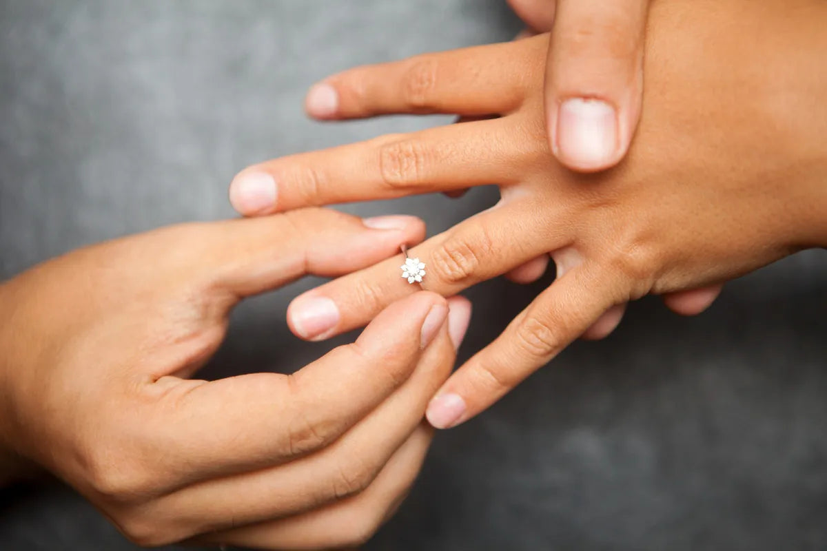 Jeweler sliding a ring onto a finger to check the size