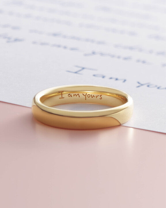 Gold band with engraved lettering on a handwritten note
