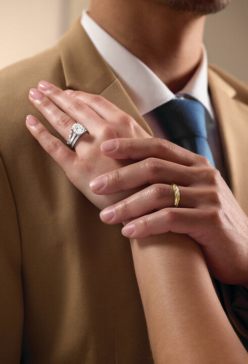 Hand with rings resting on a tan jacket sleeve